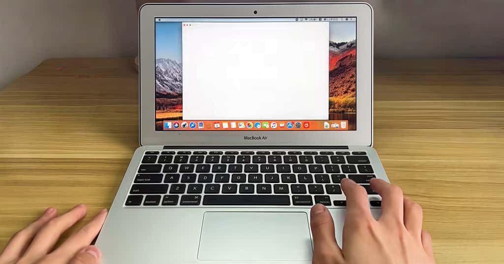 Un estudiante utiliza un MacBook Air sobre un escritorio de madera para ilustrar las mejores soluciones de expansión de almacenamiento y optimización del rendimiento para usuarios estudiantiles