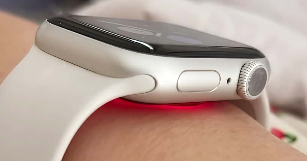 Bagian bawah Apple Watch memancarkan lampu LED merah, memantau detak jantung pengguna melalui sensor optik, menunjukkan teknologi pemantauan kesehatan berbasis cahaya