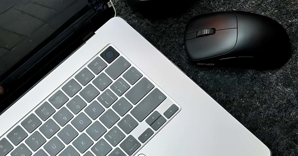 Un teclado MacBook y un ratón inalámbrico negro sobre un escritorio oscuro un ejemplo real de cinco años de uso