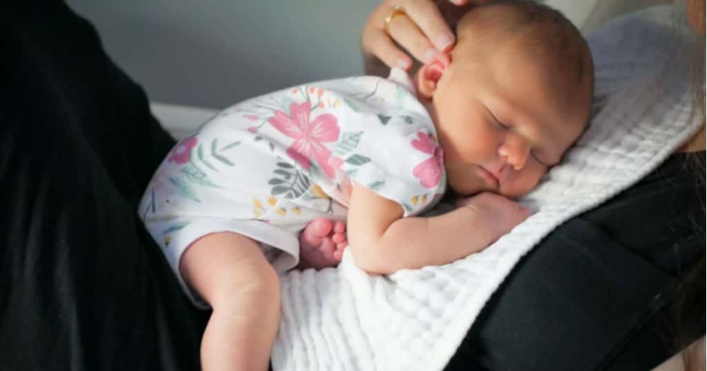 Mutter liegt ruhig da, ihr Baby schläft entspannt auf ihrem Bauch
