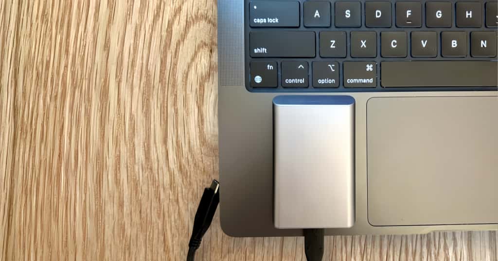 Un MacBook, conectado a un disco duro externo enchufado a uno de los puertos, ilustra cómo seleccionar y preparar un dispositivo de almacenamiento externo al realizar una copia de seguridad de un Ma