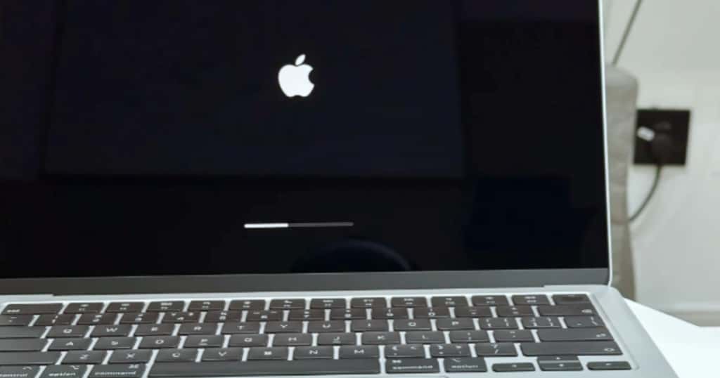 MacBook mostrando el logotipo de Apple y la barra de carga en pantalla durante el inicio en Modo Seguro, ilustración del proceso para solucionar problemas del sistema en macOS.jpg