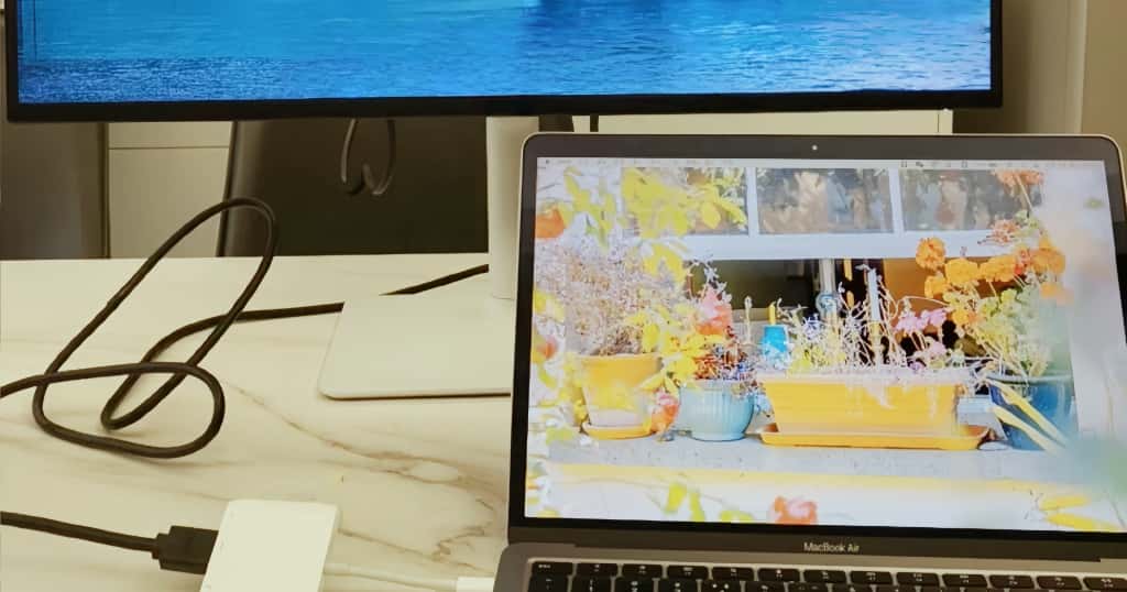 El Mac está conectado al televisor mediante un cable HDMI, lo que demuestra cómo proyectar la pantalla del Mac en el televisor utilizando un método con cable