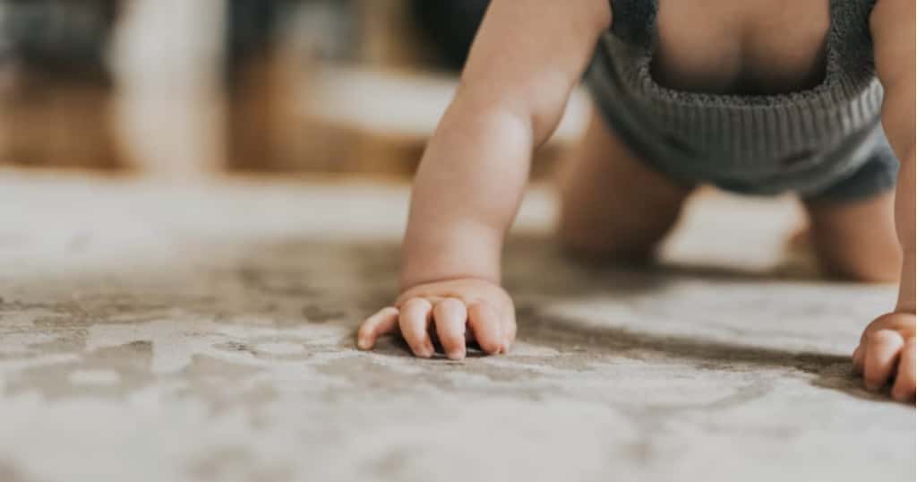 Baby krabbelt entspannt auf einem Teppich im Wohnzimmer