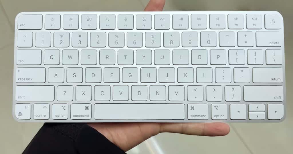 Sosteniendo un teclado inalámbrico blanco, estoy demostrando cómo elegir el teclado inalámbrico ideal y compatible para macOS